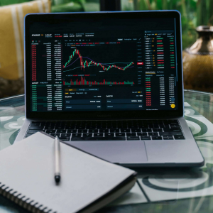 laptop z wykresem i zeszyt na szklanym stole